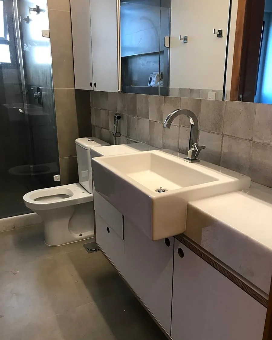 Banheiro com gabinete branco e revestimento cinza